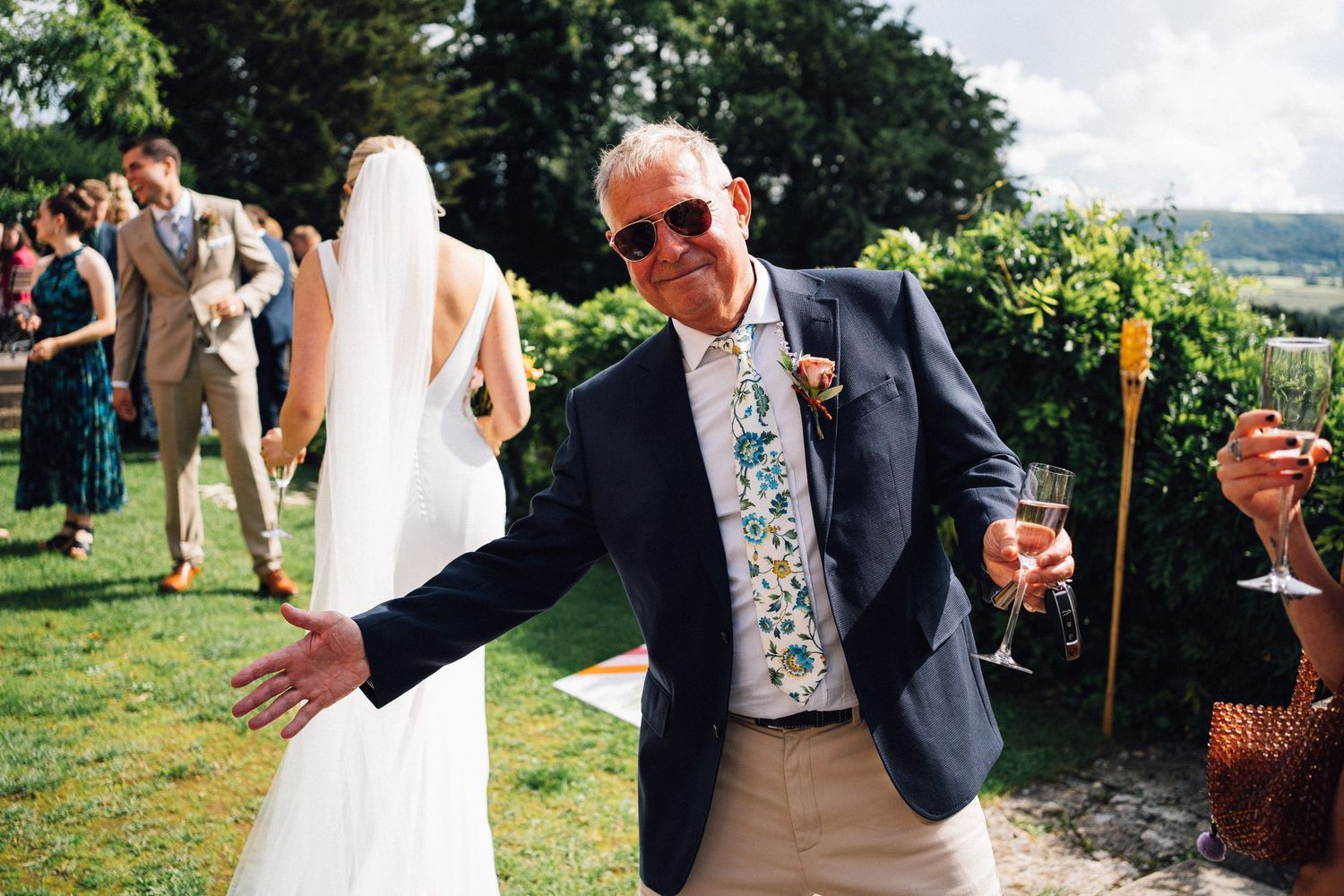 Wedding guests mingle during outdoor garden reception with countryside views.