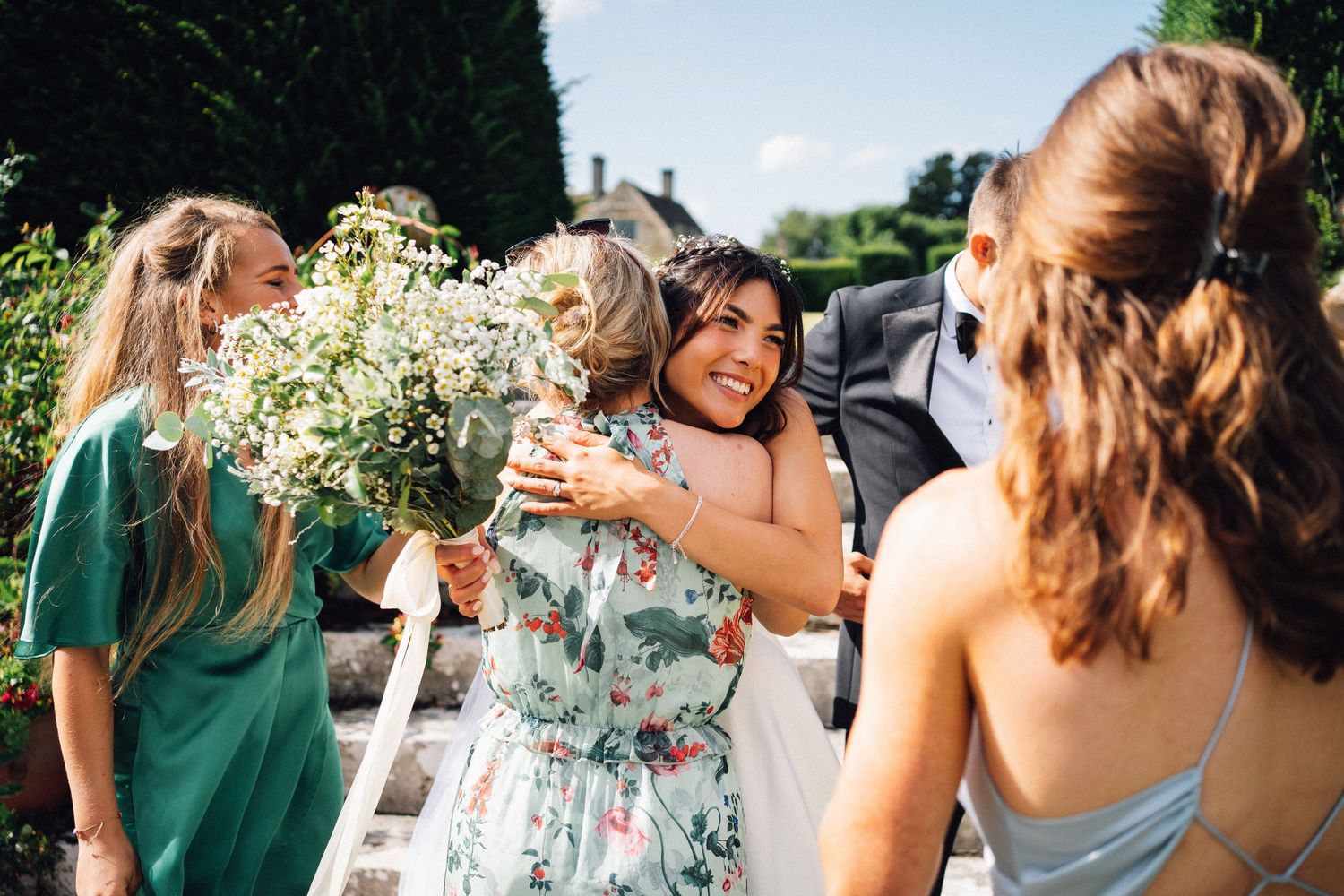 Wedding guests celebrate and hug during an outdoor summer celebration.