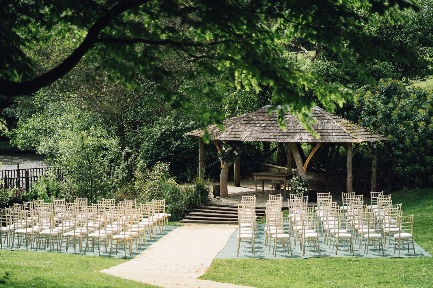 White chairs arranged in rows for an outdoor wedding ceremony with trees in the background.