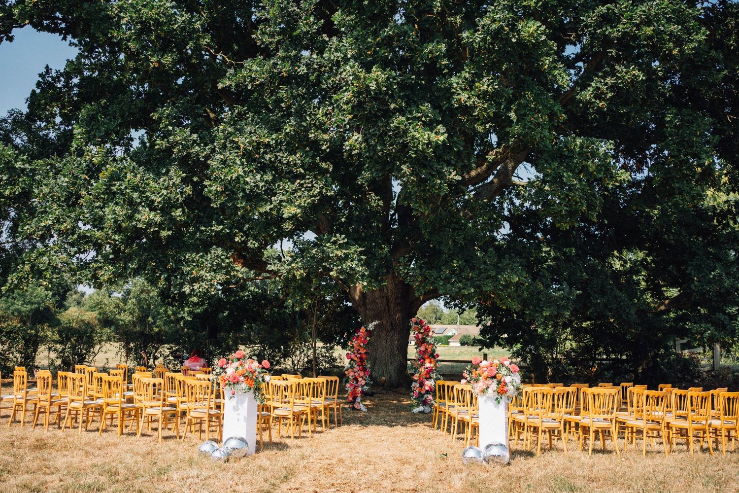 Wedding guests throw confetti and celebrate as newlyweds walk down aisle at outdoor garden ceremony.
