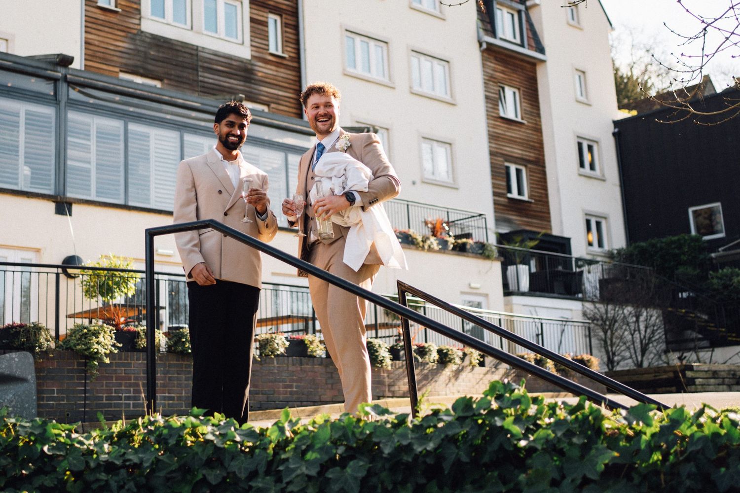 A couple in white outfits descends outdoor stairs with apartment buildings visible in the background.