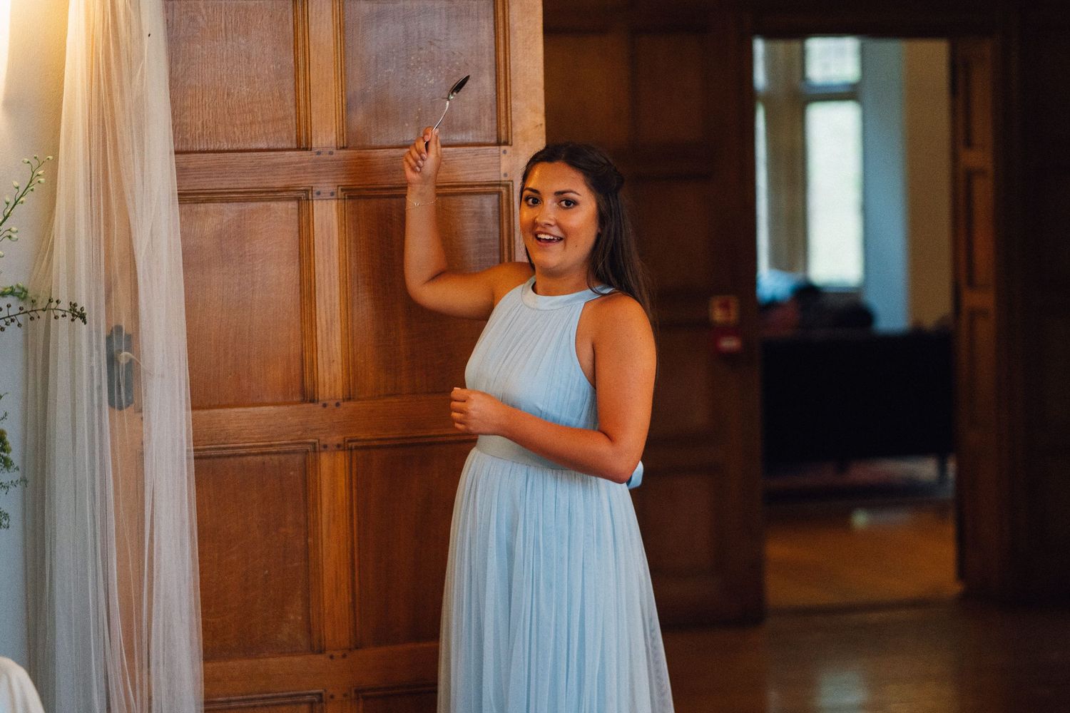 Bridesmaids in light blue dresses stand together in a wood-paneled room.