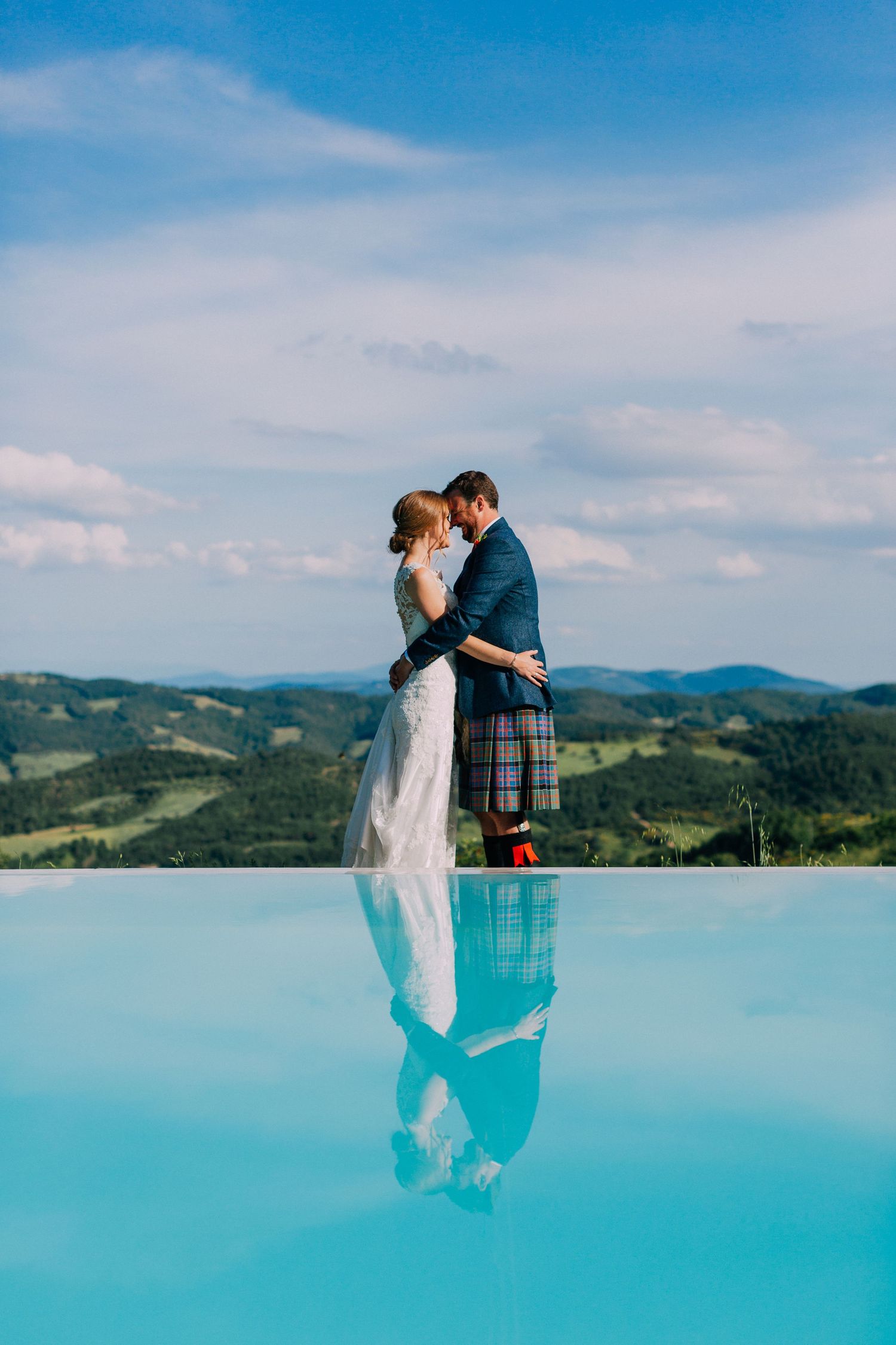 Wedding couple posing against stunning turquoise water and mountain backdrop.