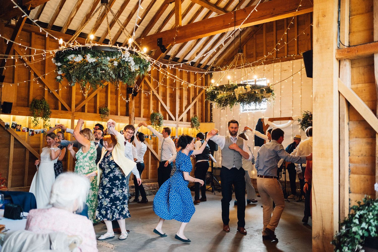 Rustic barn wedding venue decorated with string lights and wooden beams.
