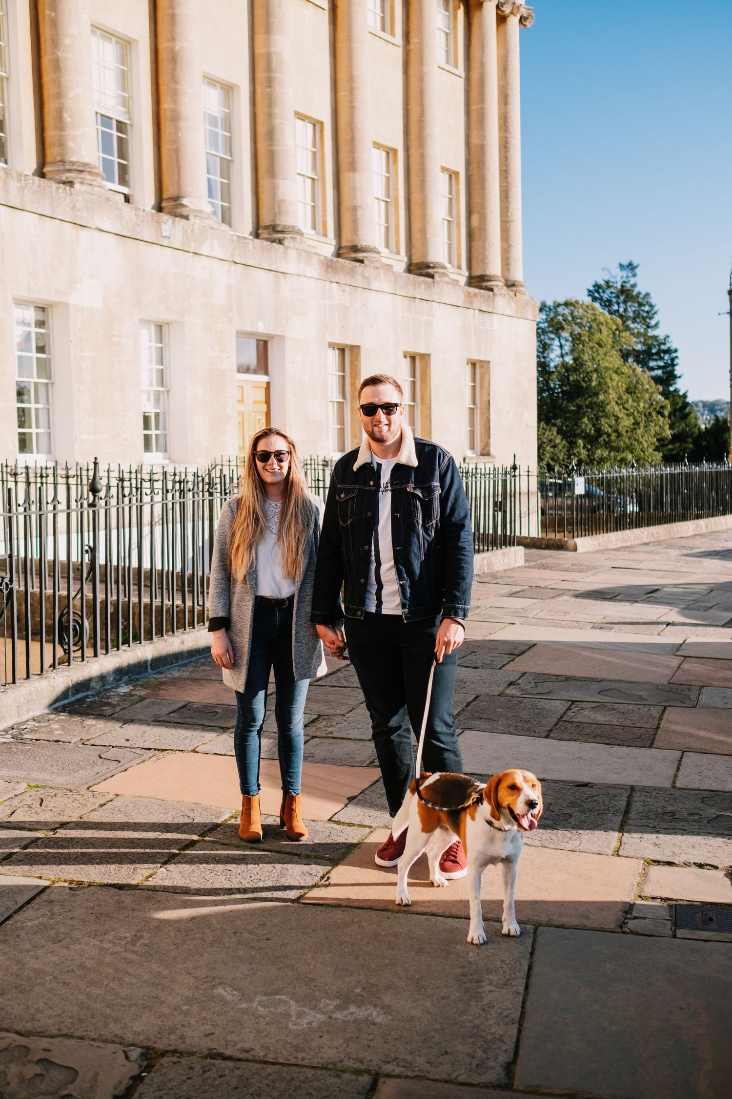 A couple walks their beagle dog along the historic Royal Crescent in Bath.
