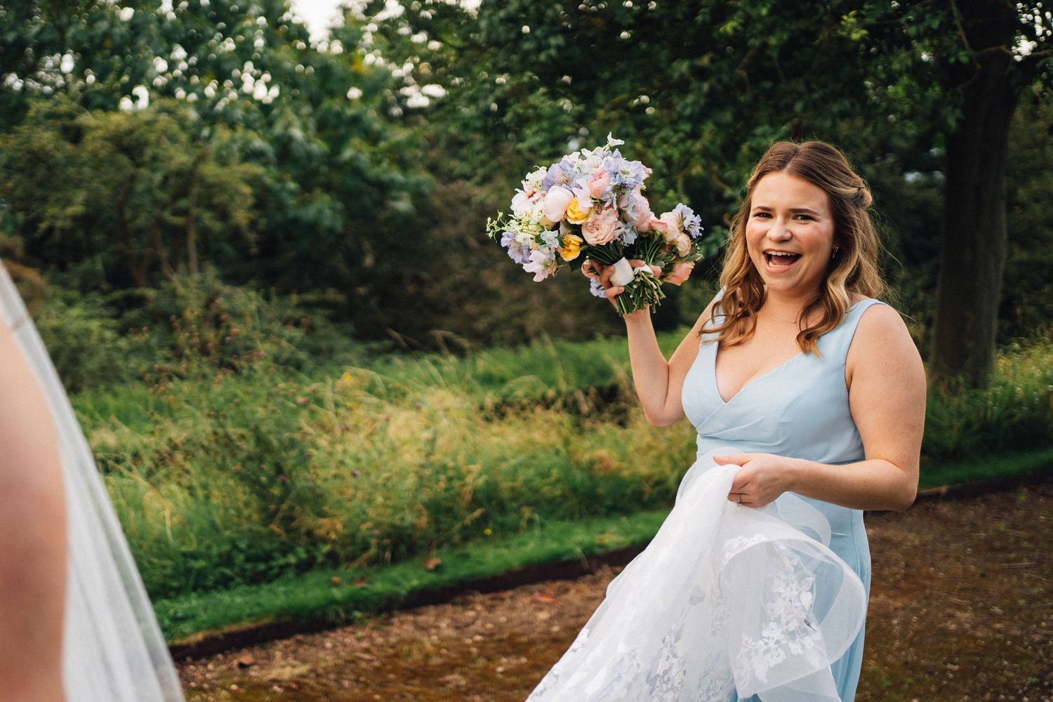 Wedding ceremony setup in a lush green garden with white chairs and floral arrangements.