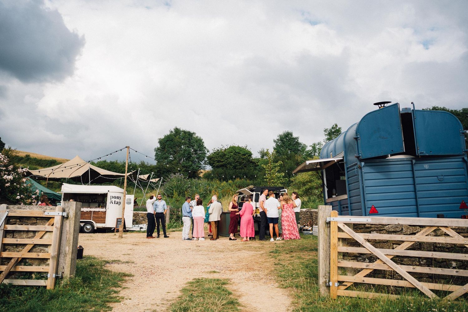 Rural farm setting with wooden gates and outbuildings for an outdoor event.