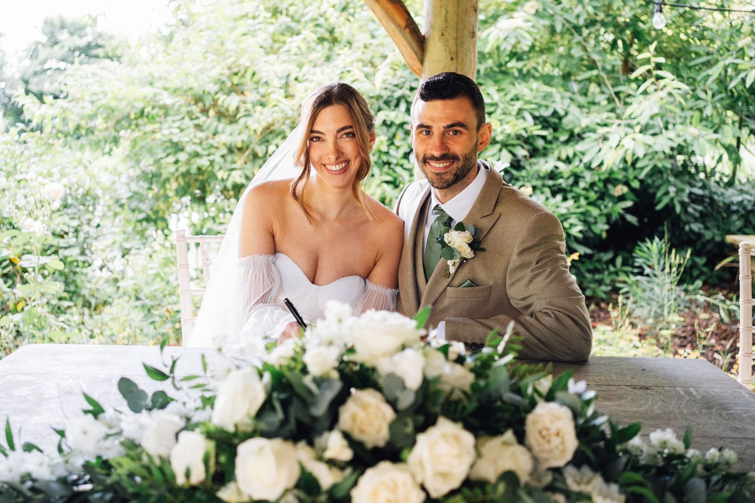 White and cream roses arranged in elegant wedding floral decorations on an outdoor table.