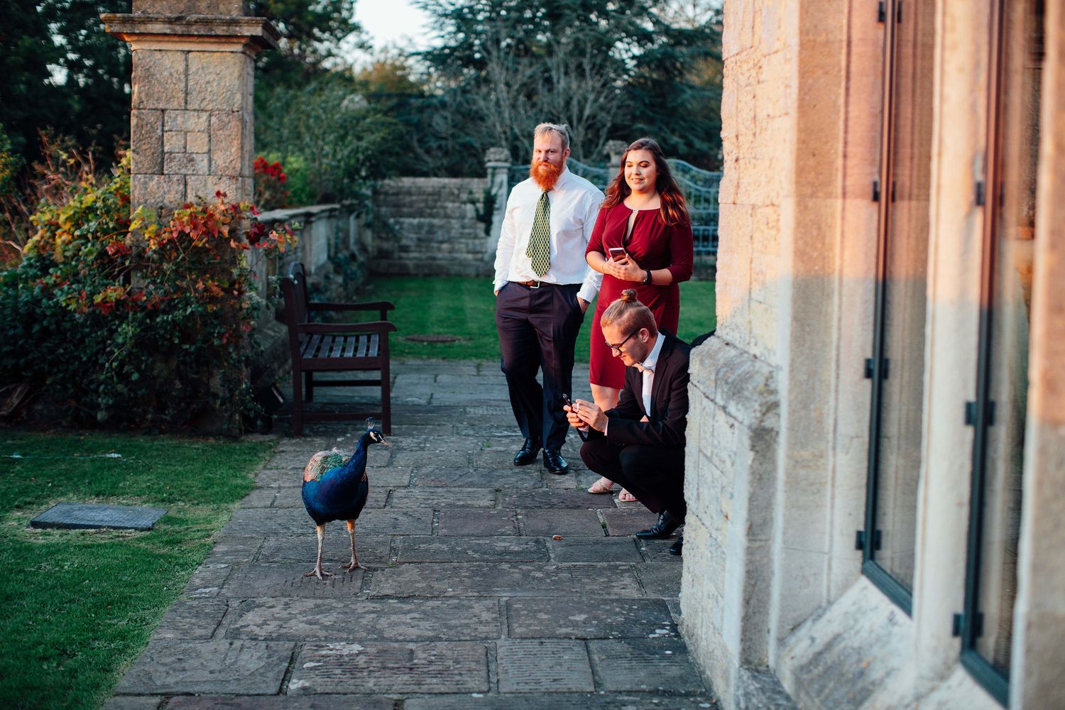 Stone building exterior with wedding guests gathering on patio during golden hour.