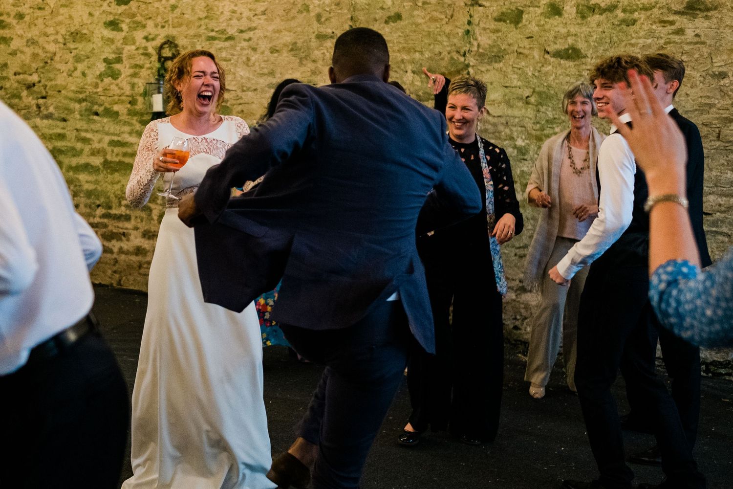 Wedding guests dancing and celebrating inside a rustic stone barn venue.