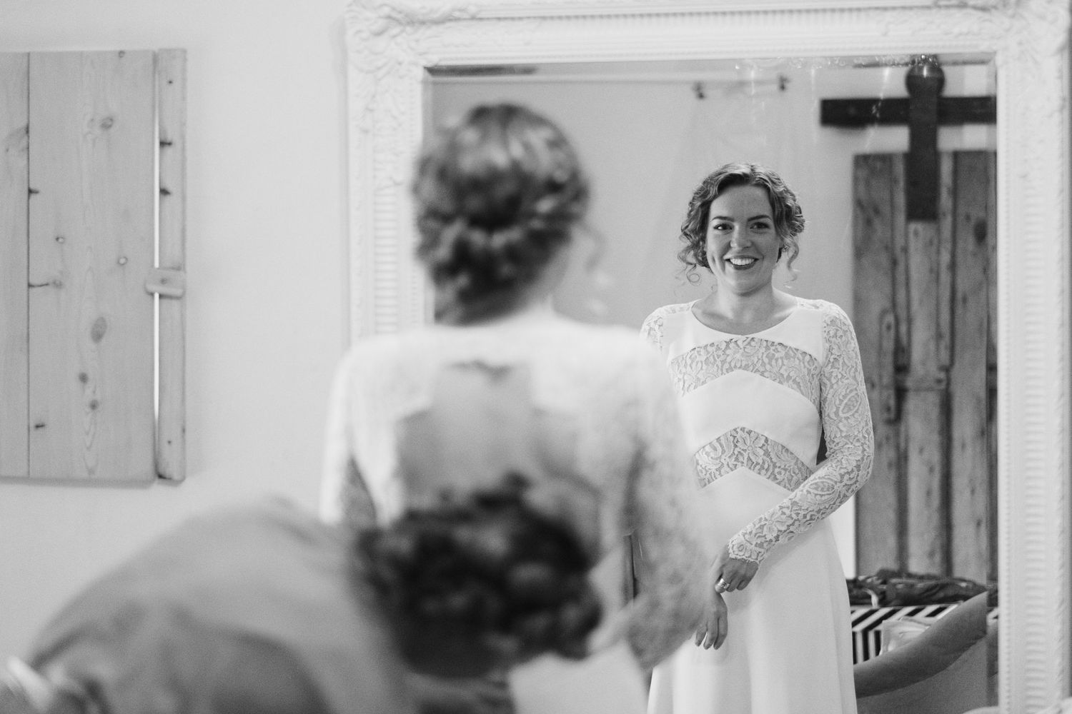 Black and white mirror reflection showing a wedding dress fitting moment.