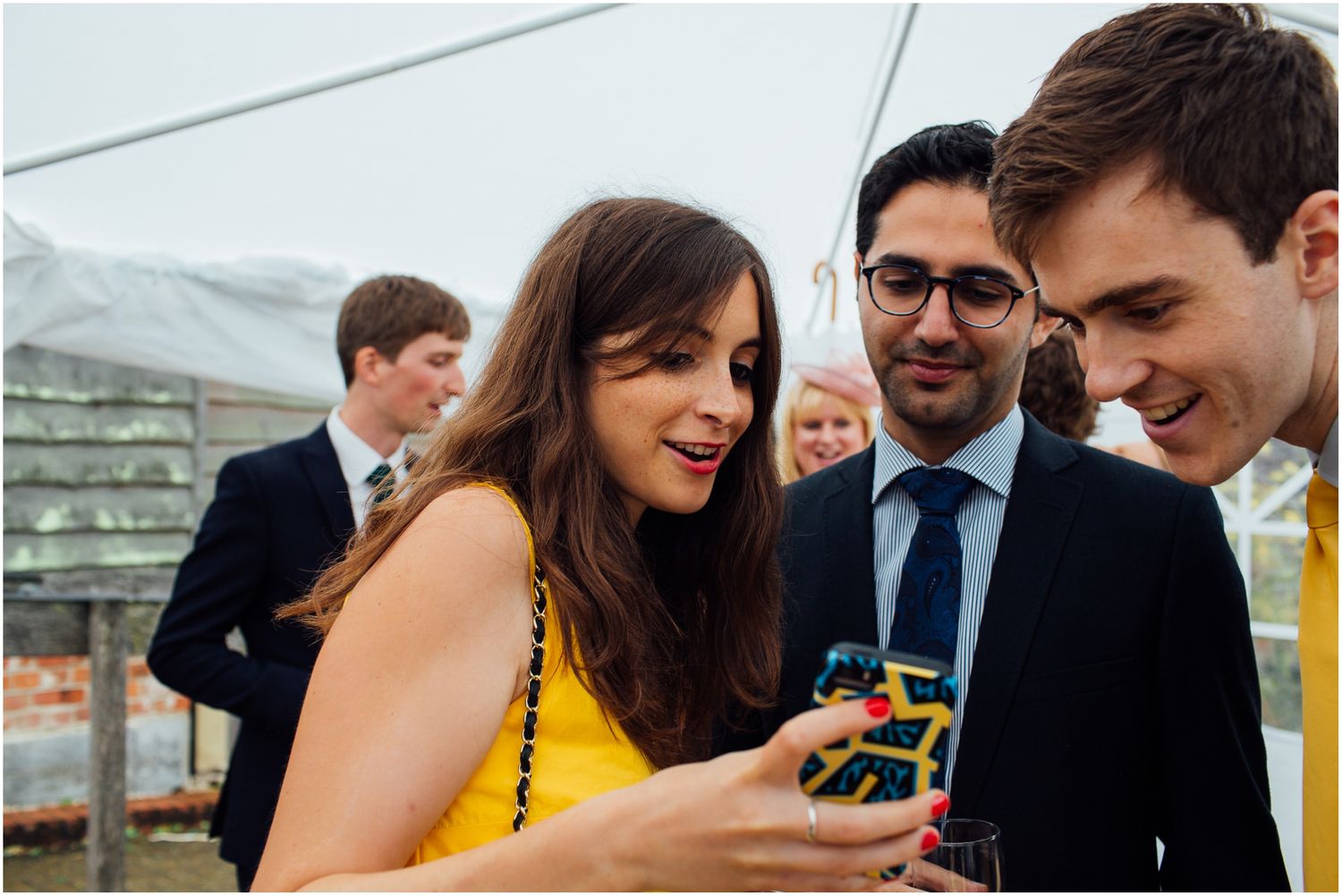 Wedding guests sharing laughter and drinks during an outdoor celebration.