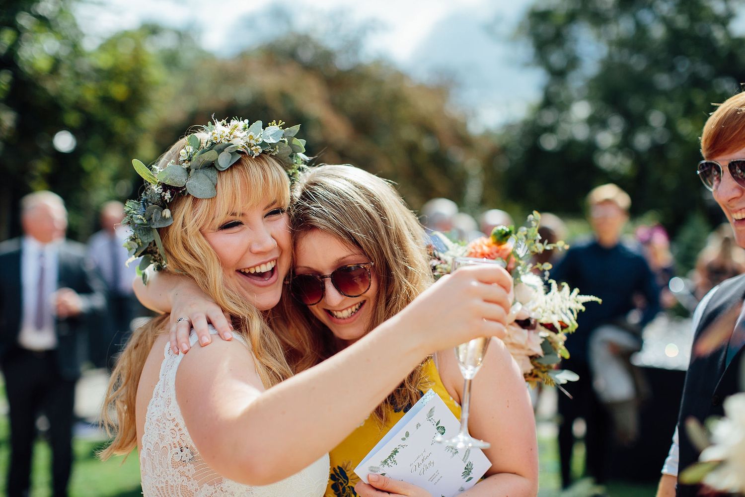 Joyful celebration at an outdoor wedding with guests embracing and laughing.