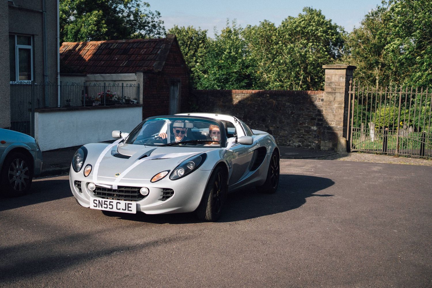 A sleek white McLaren sports car parked in front of a brick building on a sunny day.
