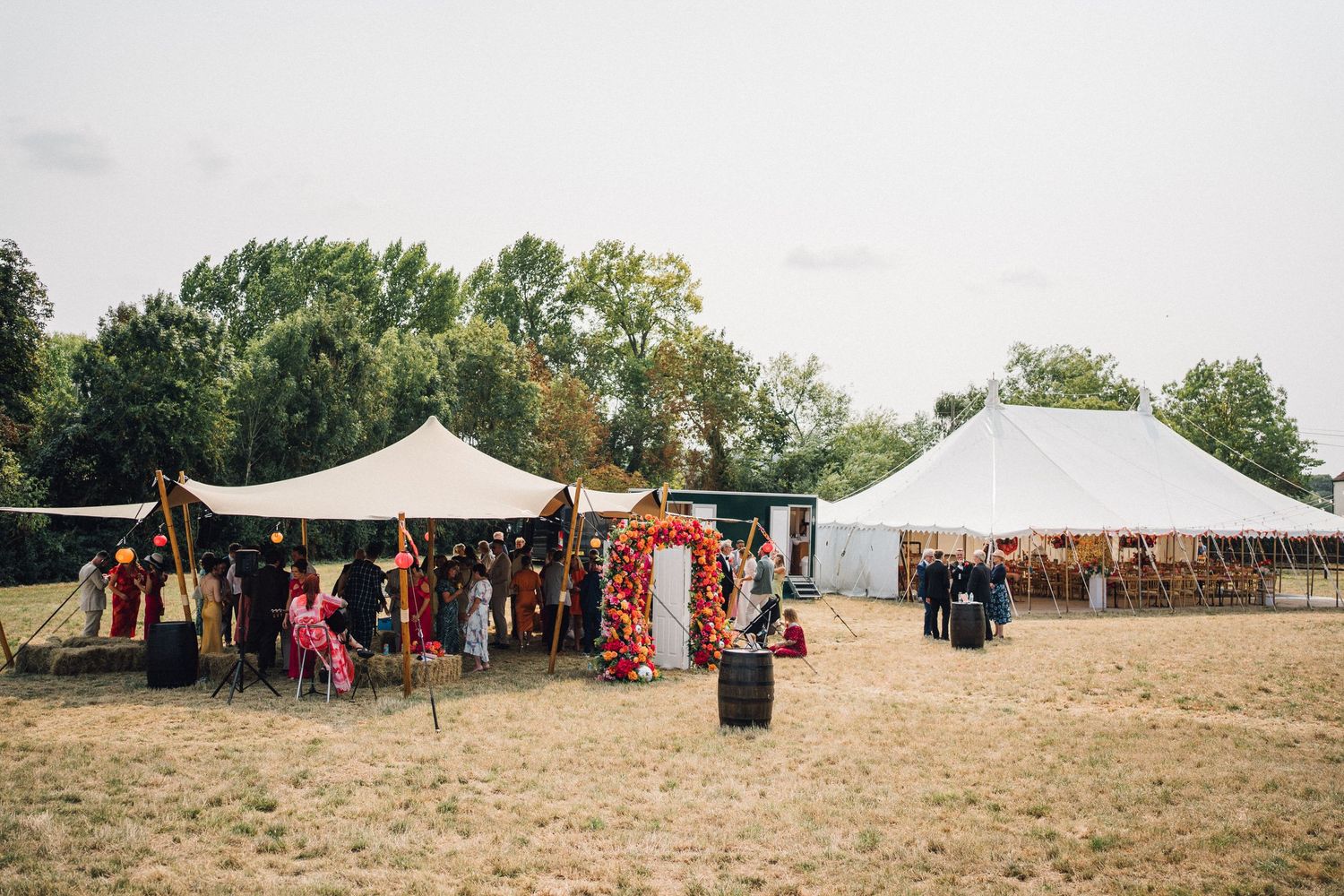 A panoramic view of white tents and festival attendees gathered on a grassy hillside during an outdoor event.