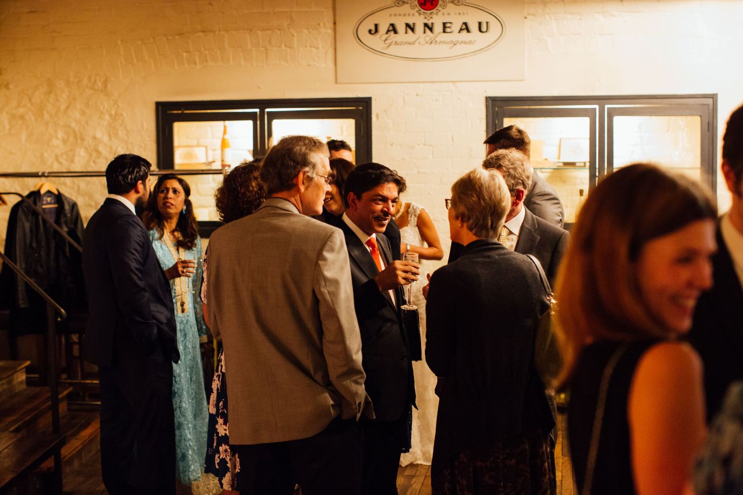 A warm, dimly lit restaurant interior shows people gathering and socializing during an evening event.