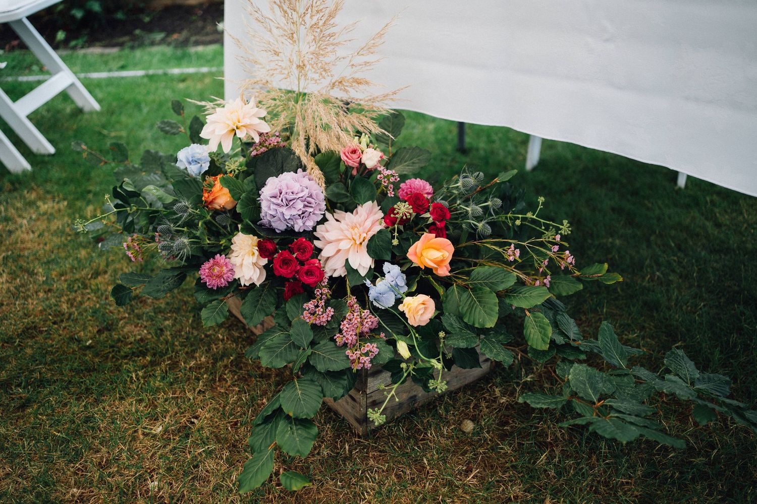Romantic floral arrangements with pink and peach roses adorn a garden wedding venue.