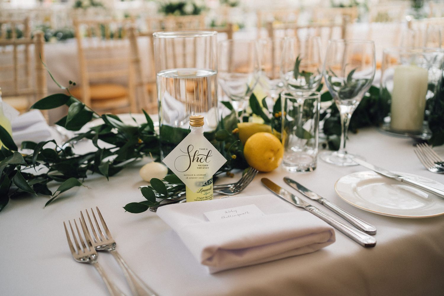 Wedding table settings with greenery, white linens, and elegant place settings.