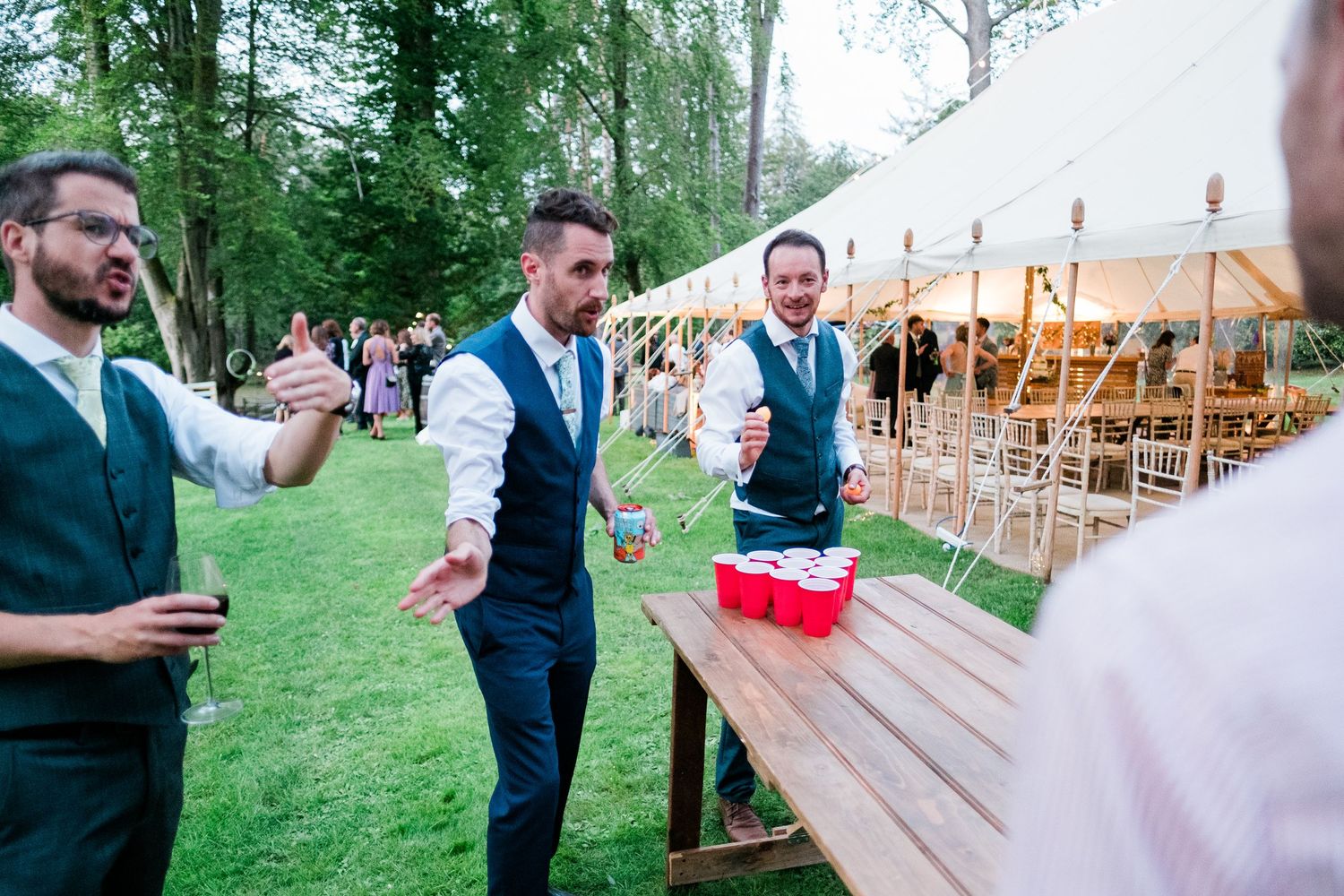 Outdoor wedding reception features lawn games and a large white tent in a garden setting.