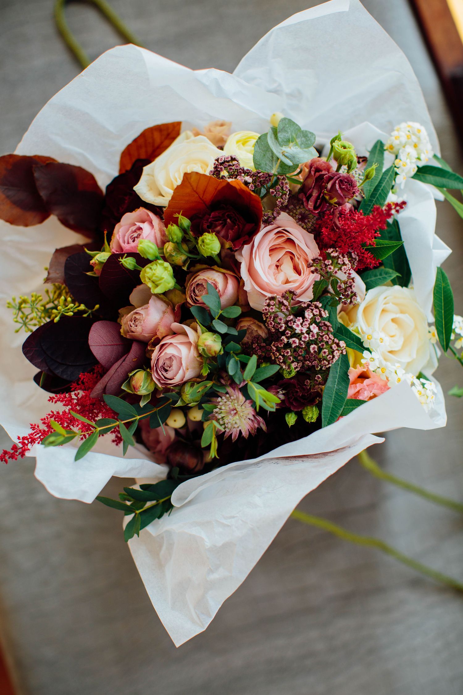 Elegant floral arrangement with pink roses and mixed flowers wrapped in white paper.