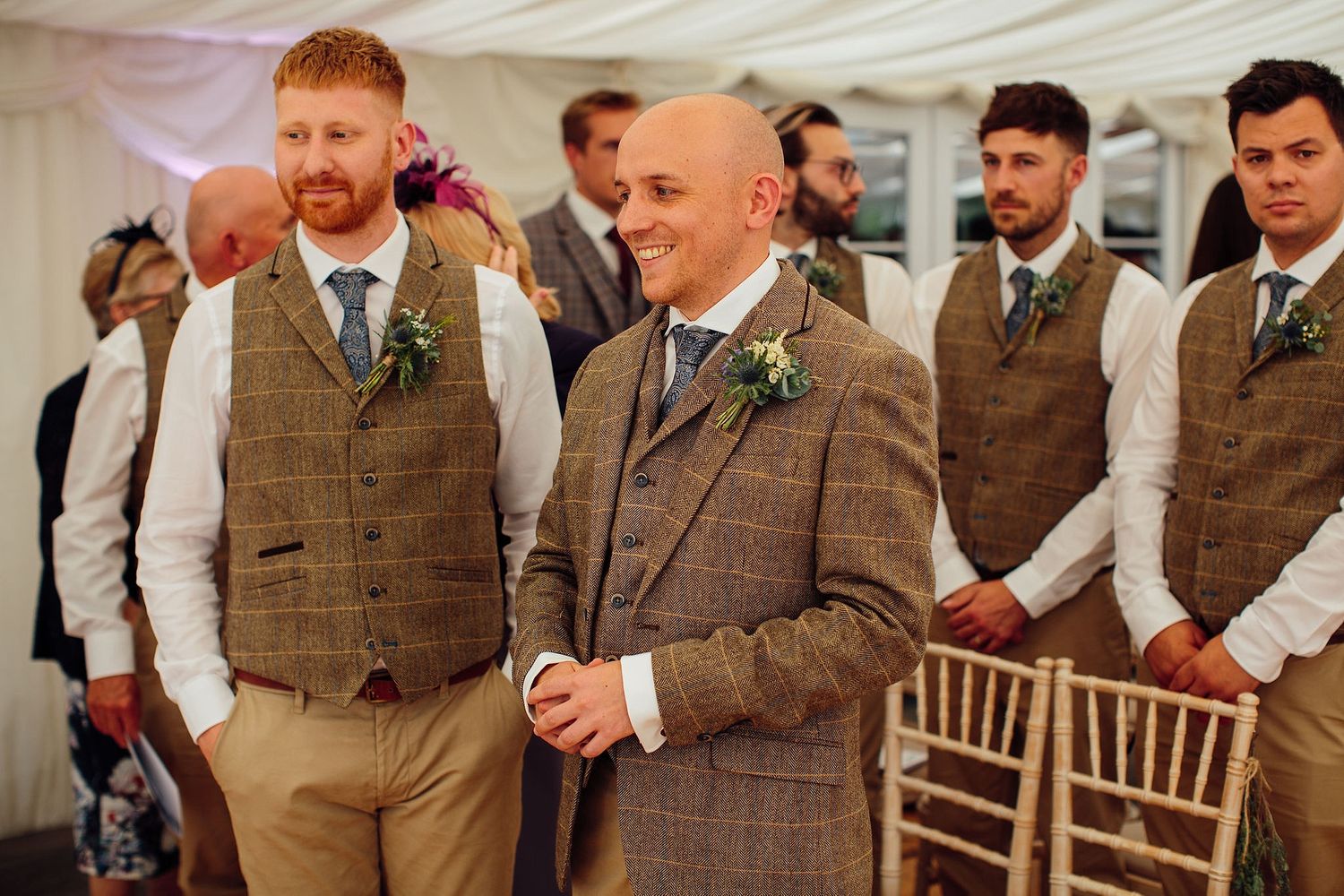 Groomsmen in tweed vests and formal attire stand together during wedding celebrations.