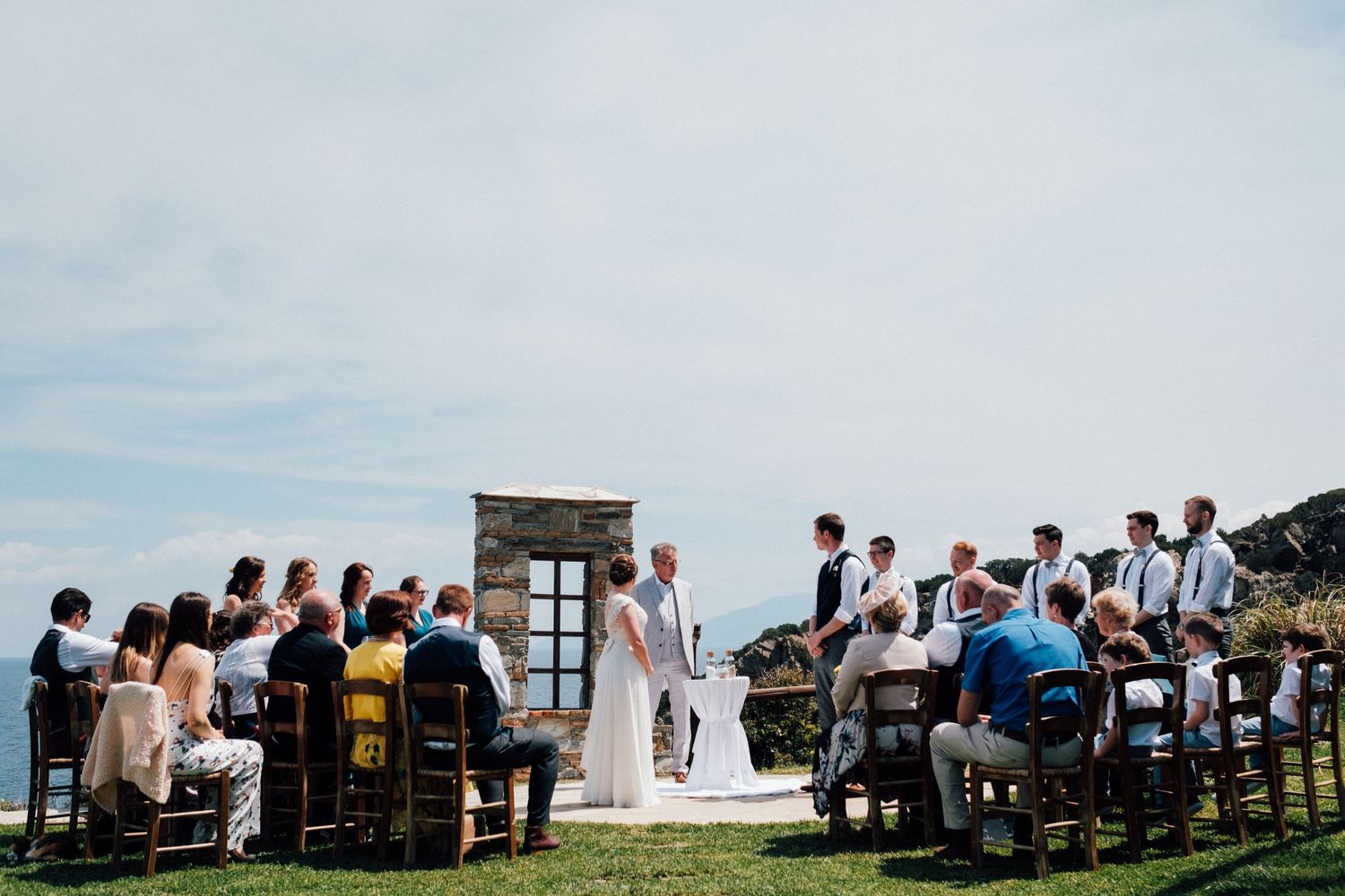 Wedding ceremony setup with guests seated outdoors overlooking coastal views.