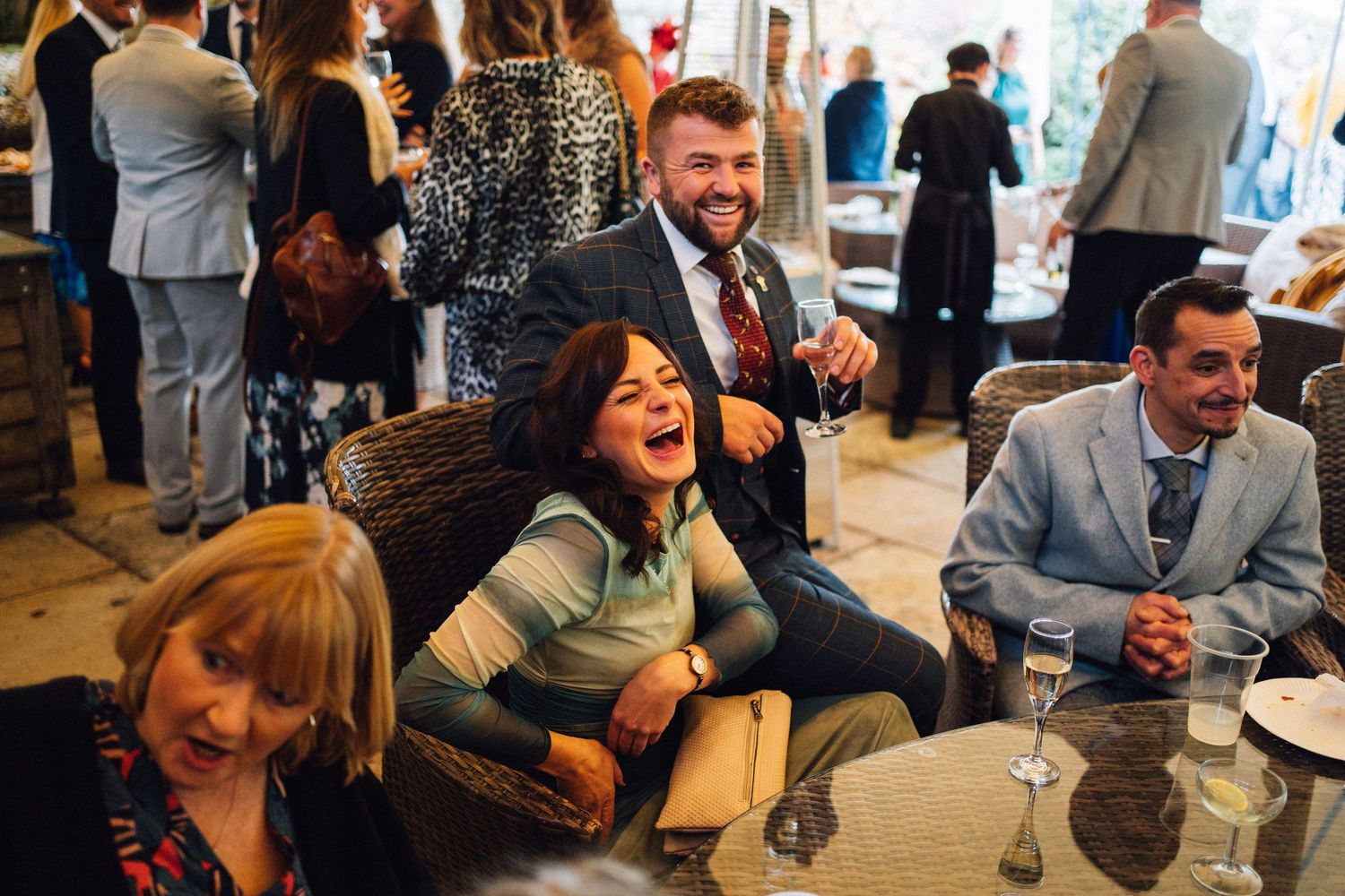 A group of people laugh together while sitting at a table during a social gathering.