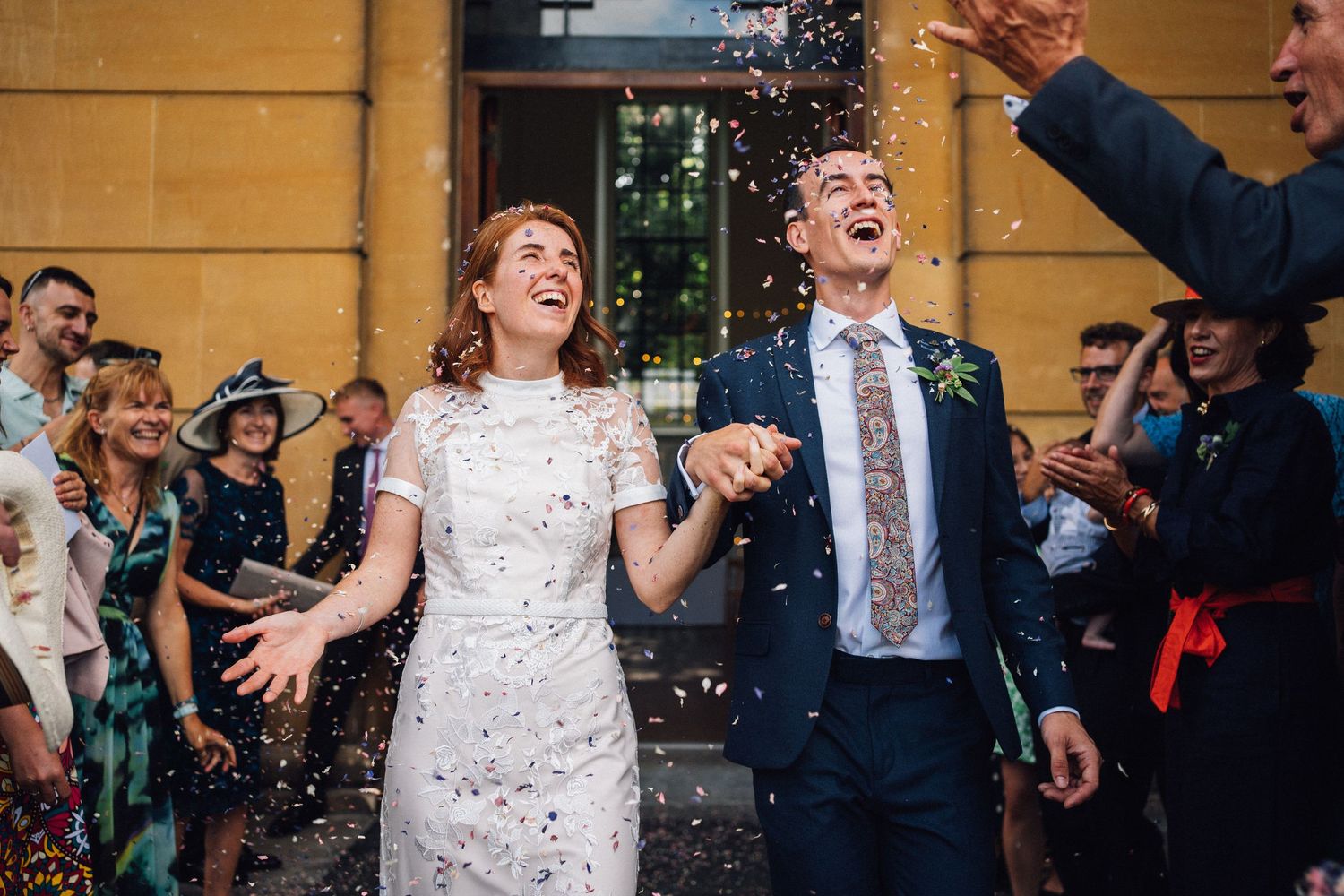 Joyful celebration with confetti outside historic stone building.