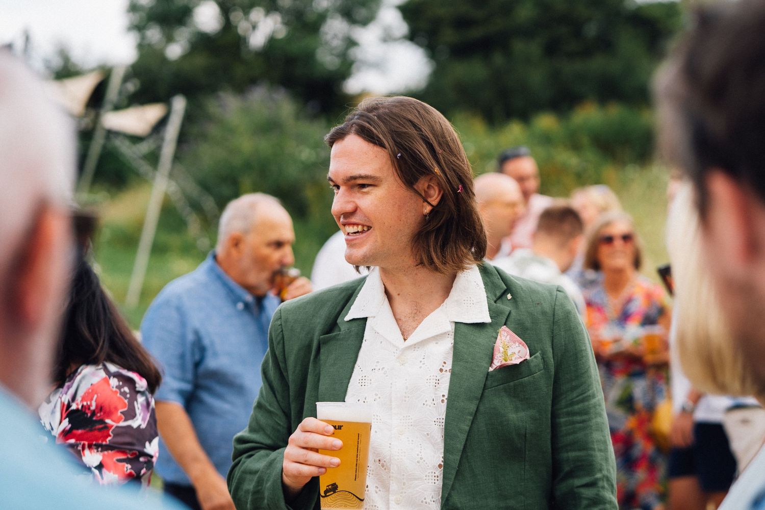 Guests mingle and celebrate at an outdoor wedding reception with drinks and laughter.