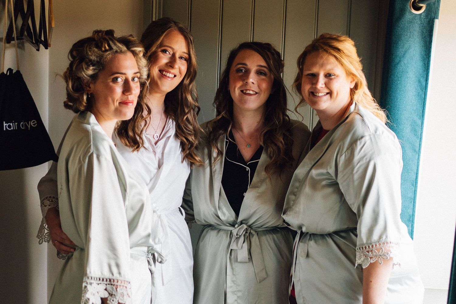 Group in matching white robes share joyful moment during wedding preparations.