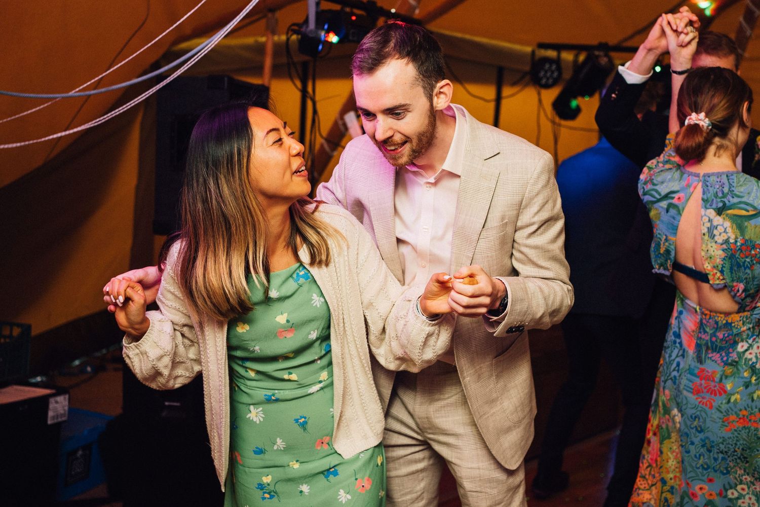 Couples dancing and enjoying themselves at a lively indoor reception party with warm lighting.