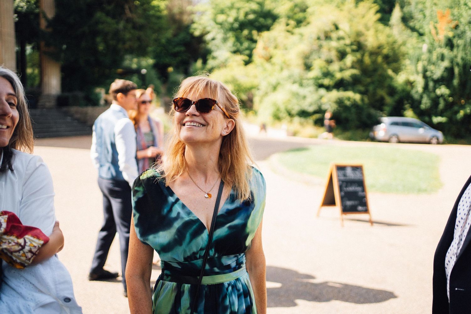 A group of people walking and mingling at an outdoor event on a sunny day.