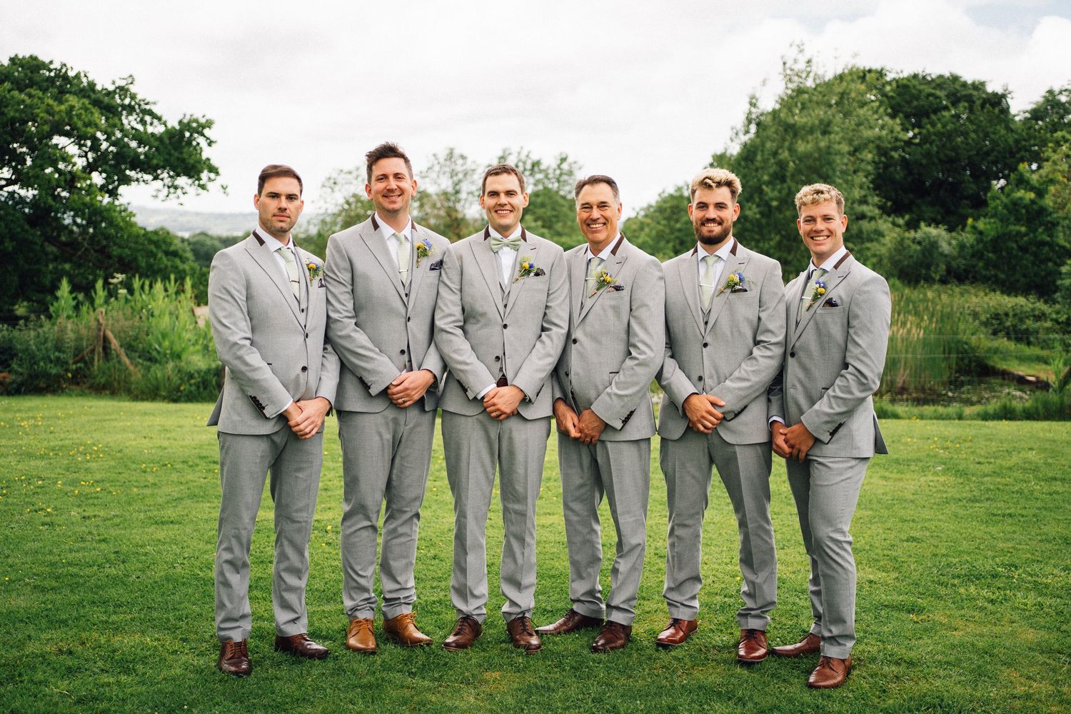 Groomsmen in grey suits showing off their colorful socks in outdoor photo.