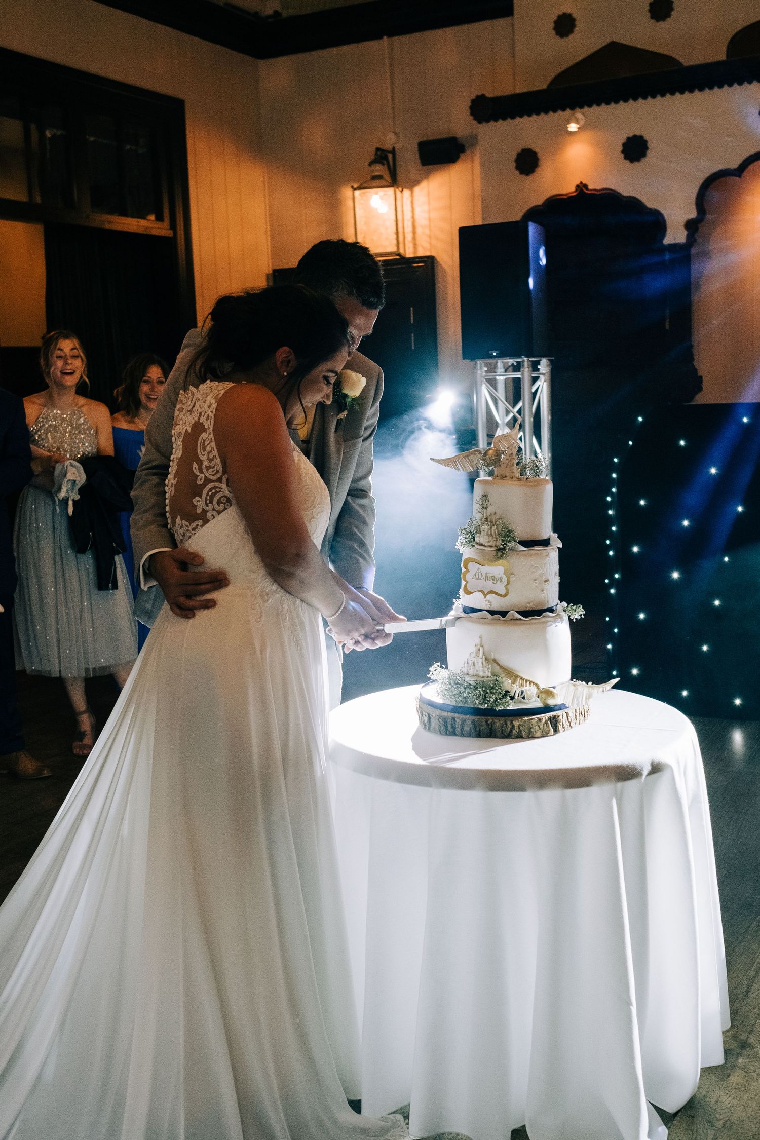 Wedding reception venue with elegant cake display and dramatic lighting effects.