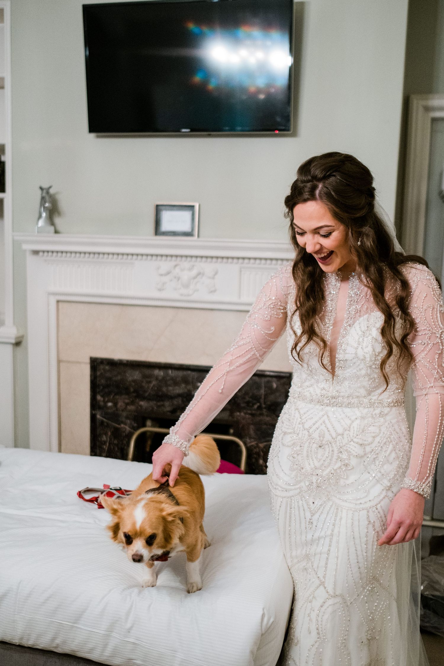 A small dog sits on a white couch next to flowing wedding dress fabric in an elegant room.