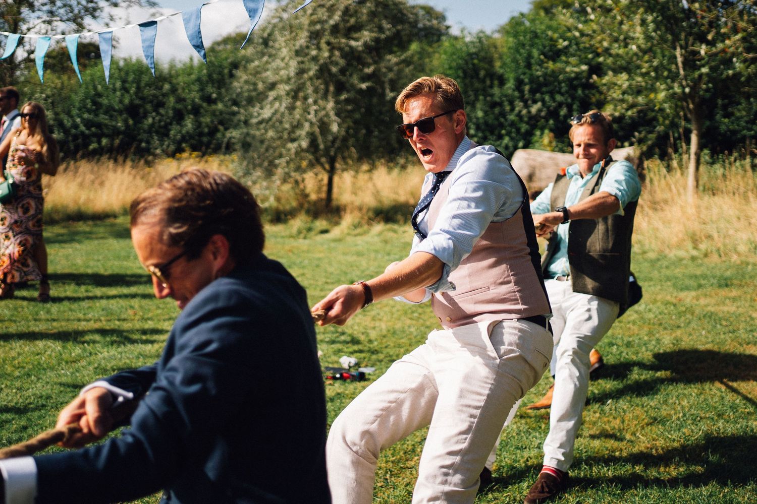 People dancing and enjoying themselves at an outdoor summer party with string lights and trees in the background.