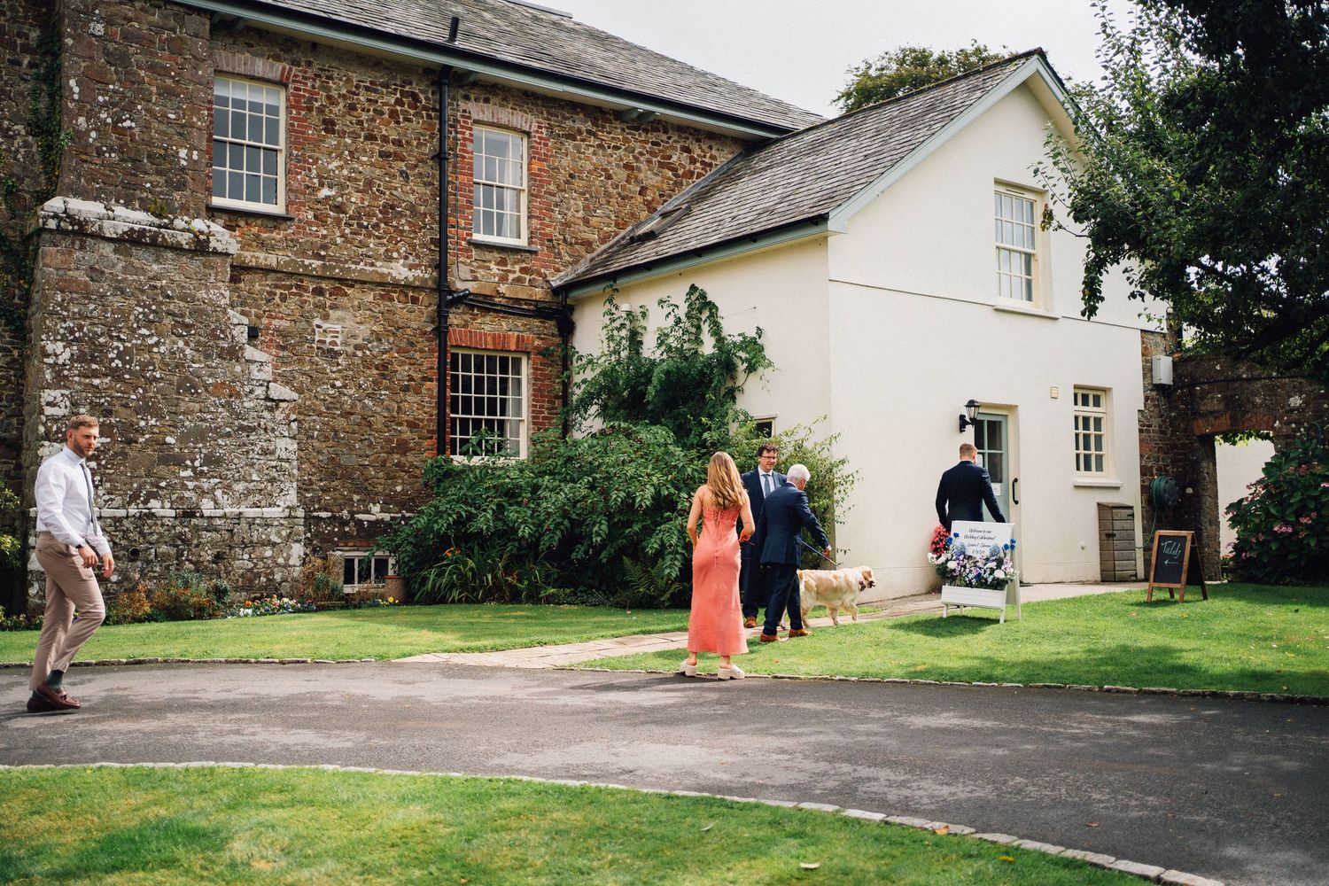 Mixed stone and white painted country house exterior with manicured lawn and walkway.