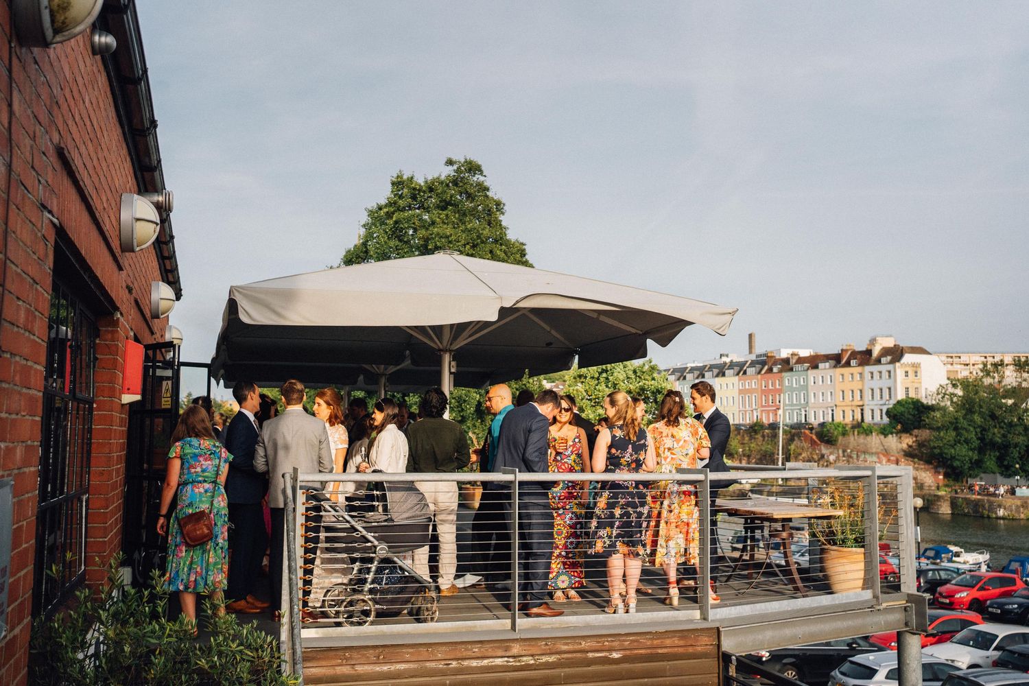 Panoramic view of wedding guests gathered on an outdoor brick terrace.