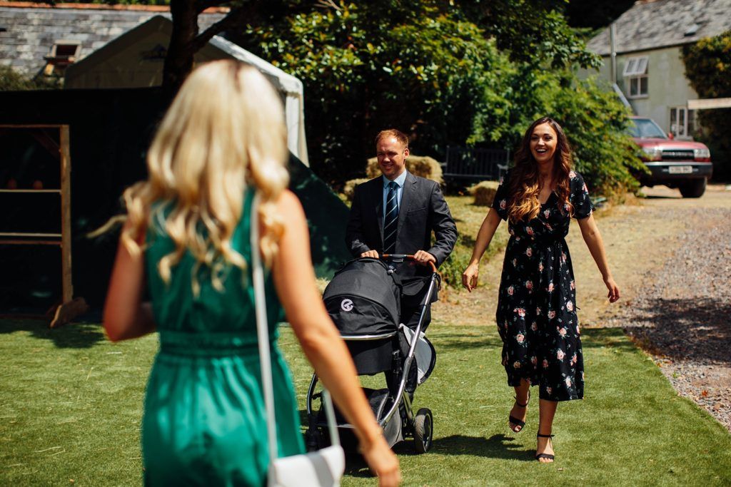 Outdoor wedding scene with guests in summer attire on a sunny lawn.