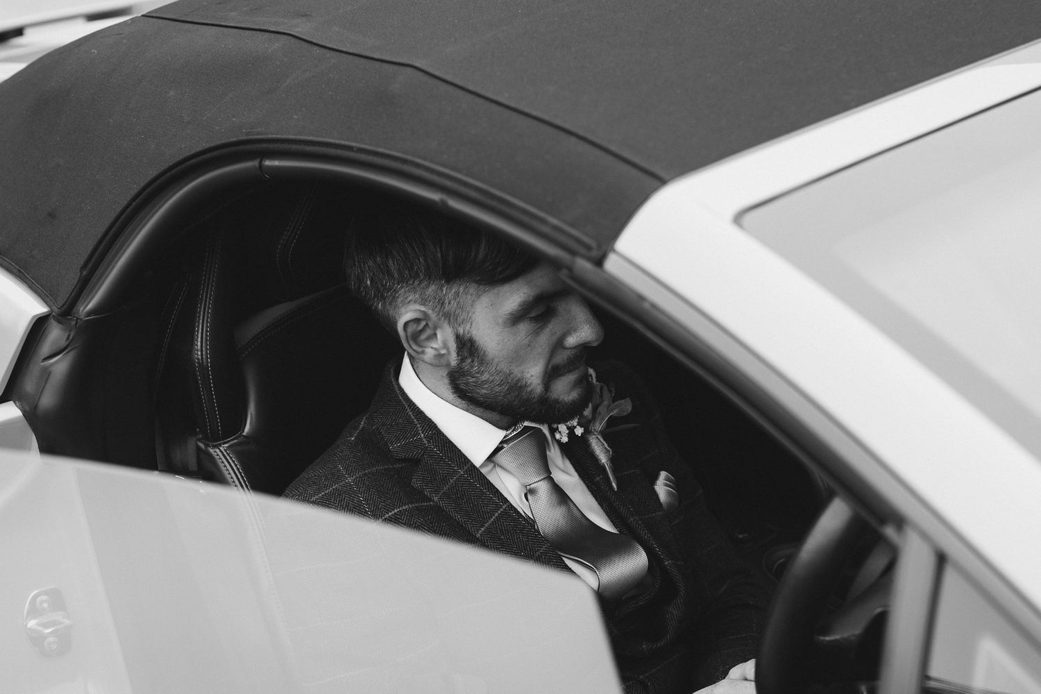 A person in formal attire seated in a luxury vehicle.