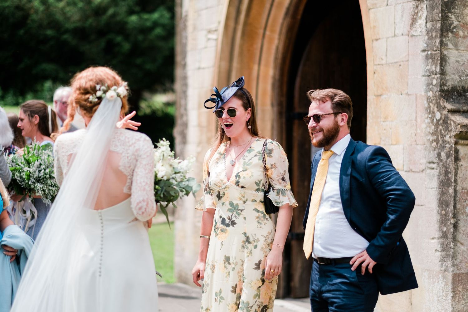 Wedding guests mingle beneath stone archway during outdoor celebration.