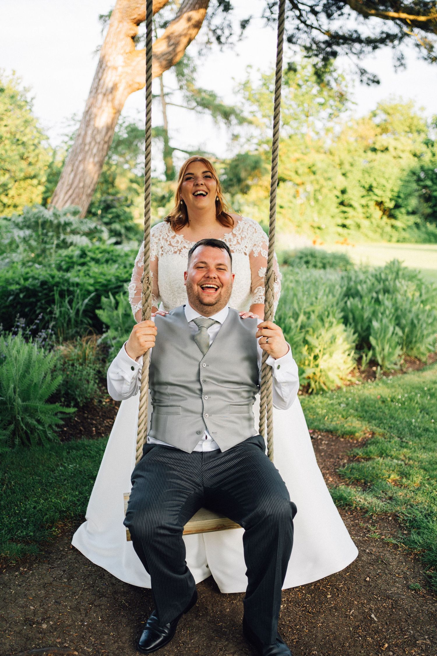 Person enjoying a swing outdoors wearing formal attire and laughing joyfully.