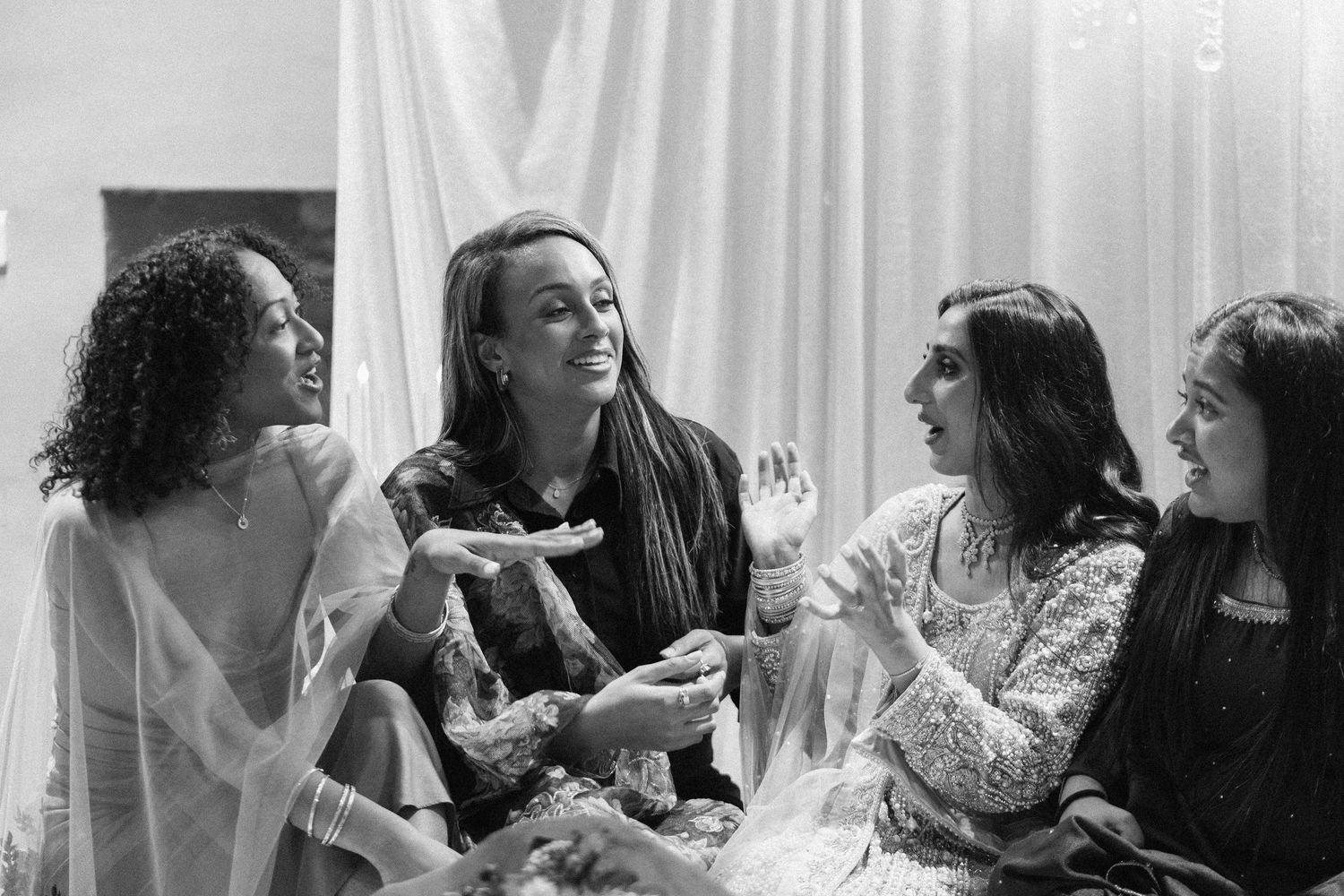 A candid black and white photo of friends celebrating at a wedding party.