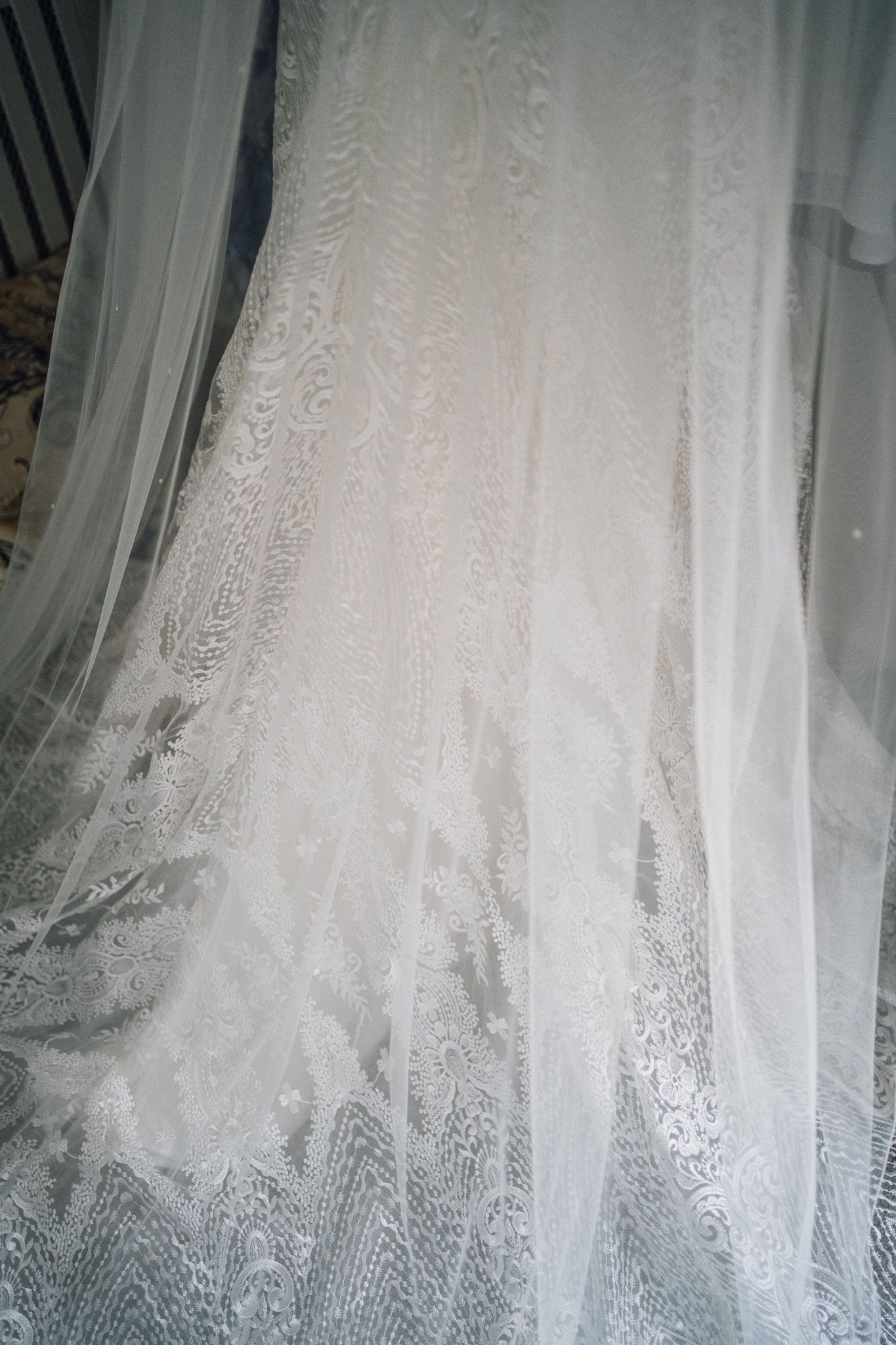 Delicate white lace wedding dress details with intricate floral patterns and sheer fabric.
