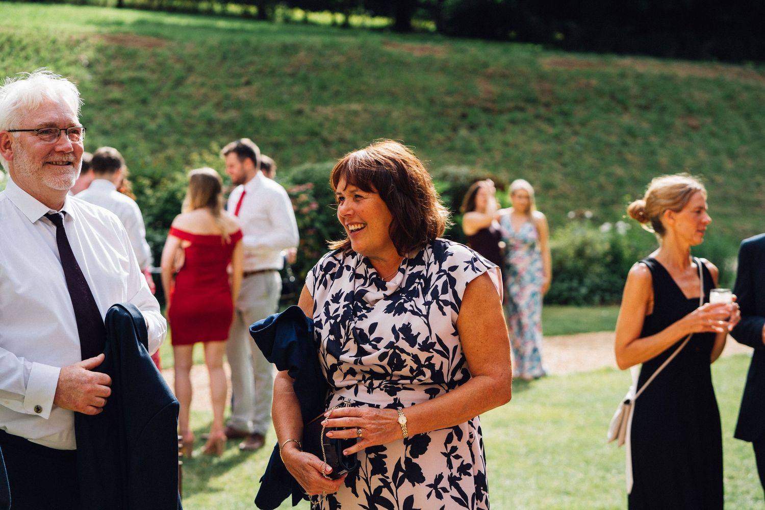 Wedding guests mingling on a sunny lawn during an outdoor reception.