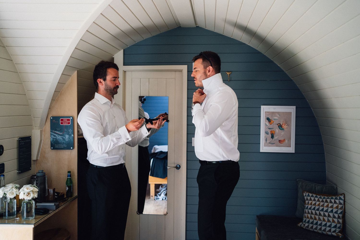 A sequence of candid moments showing guests getting ready in a rustic indoor setting with white paneled walls.