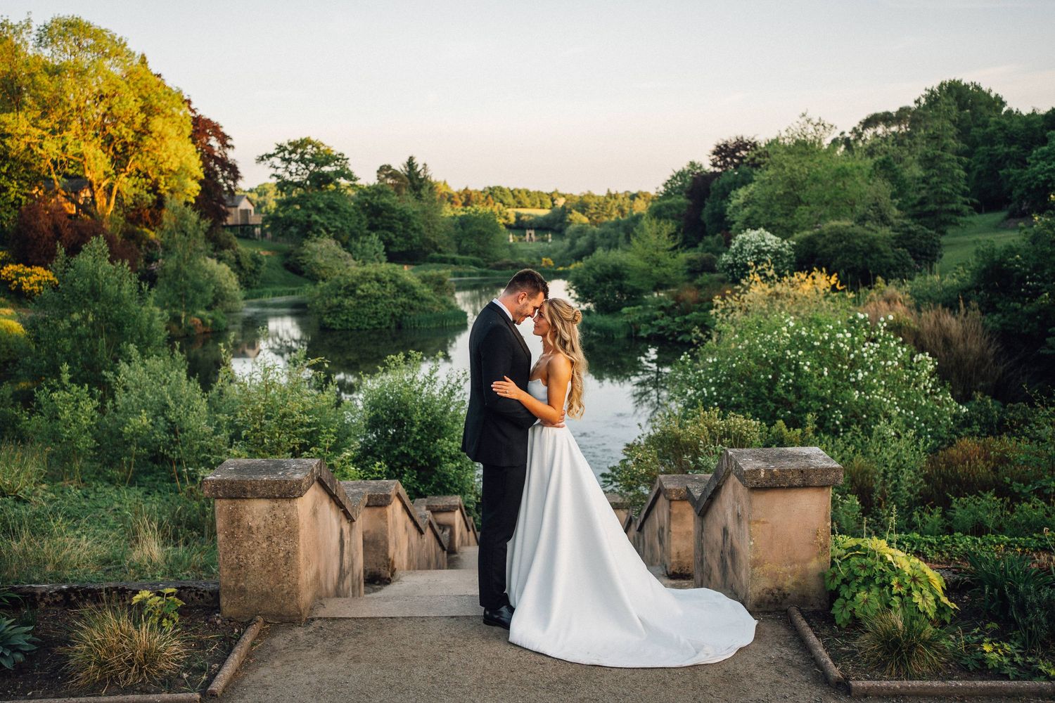 A romantic wedding couple poses in a lush garden setting during golden hour with multiple panoramic views.