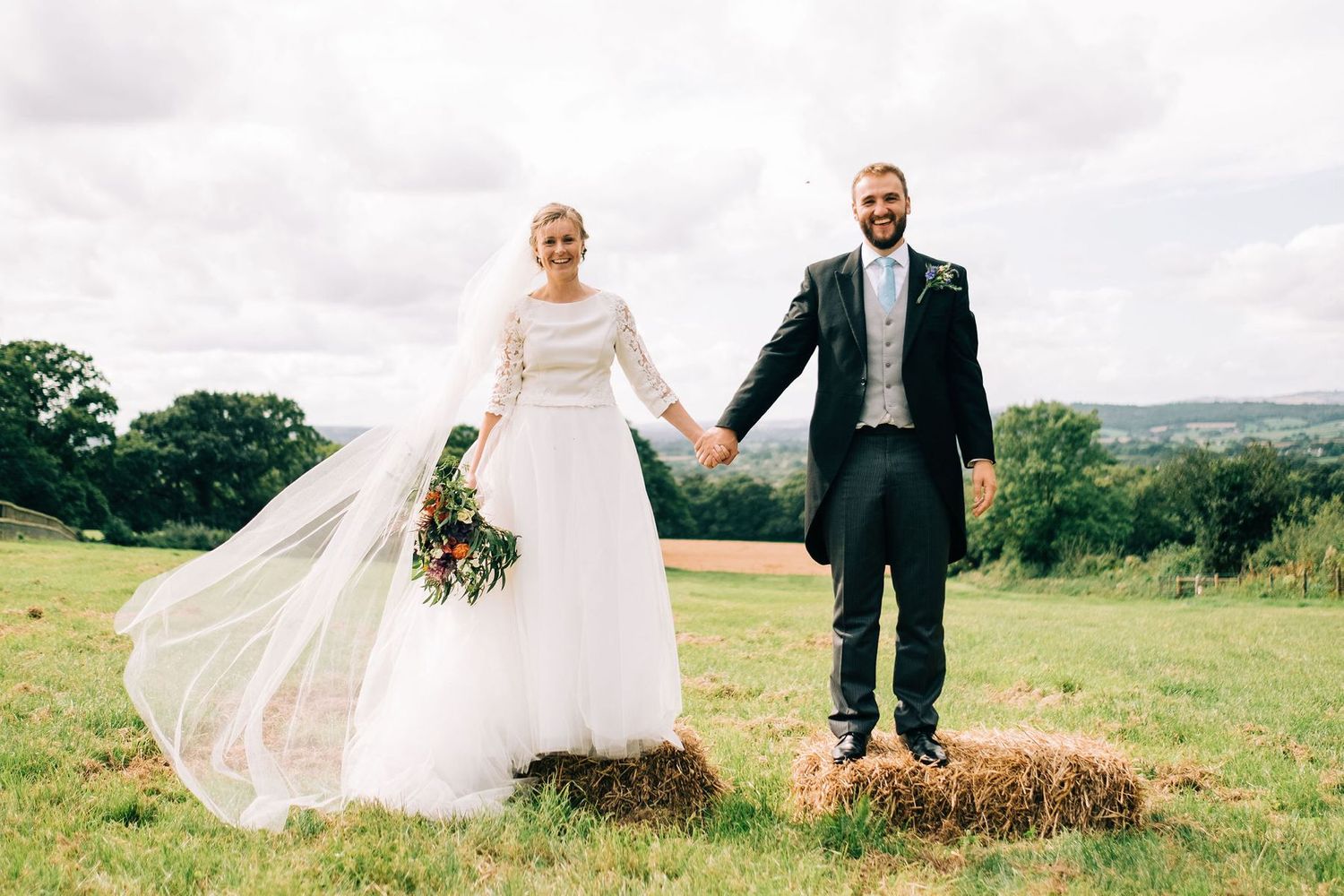 Wedding couple walking hand in hand through a rustic farm setting.