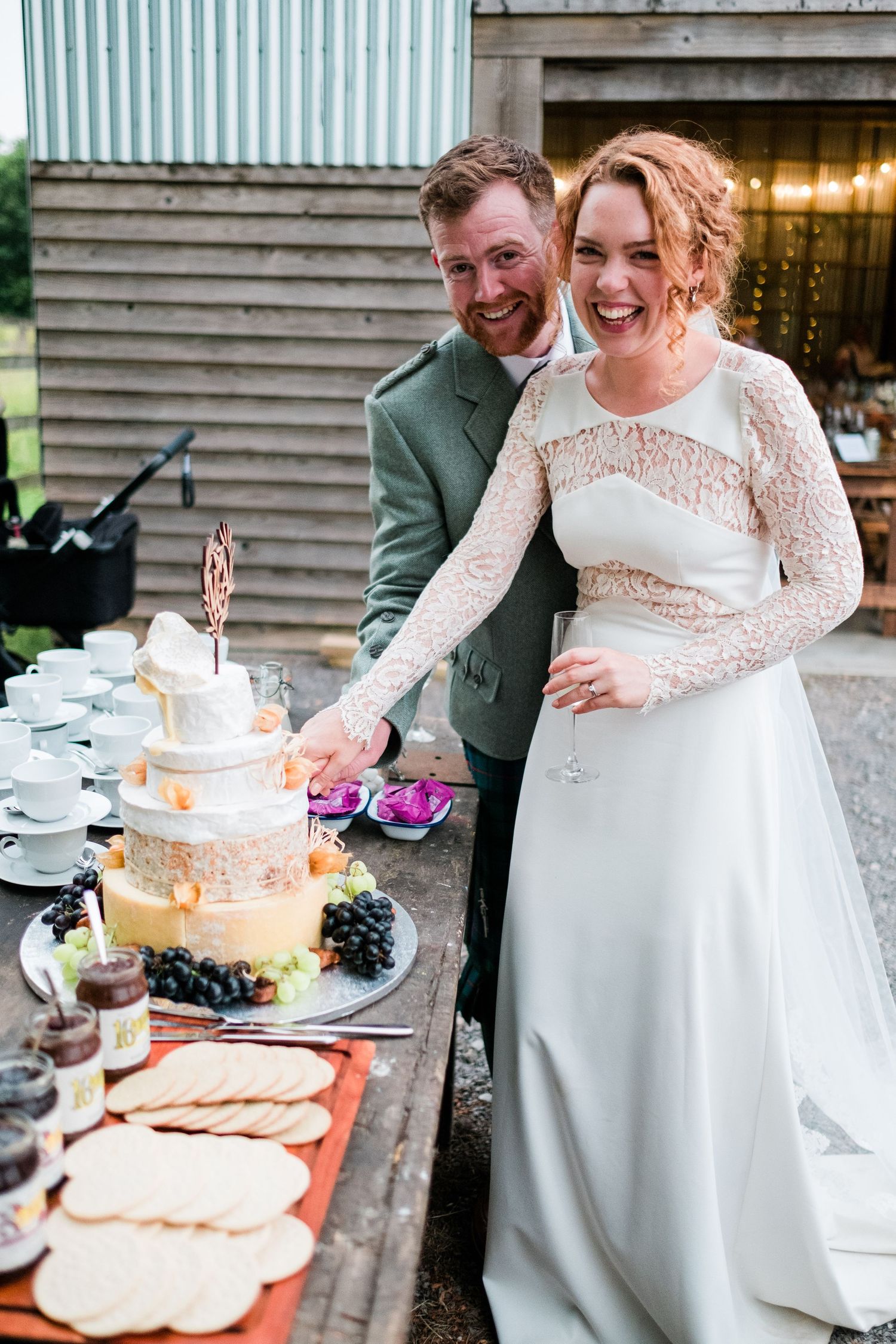 Wedding couple sharing a joyful moment while cutting their white tiered cake.