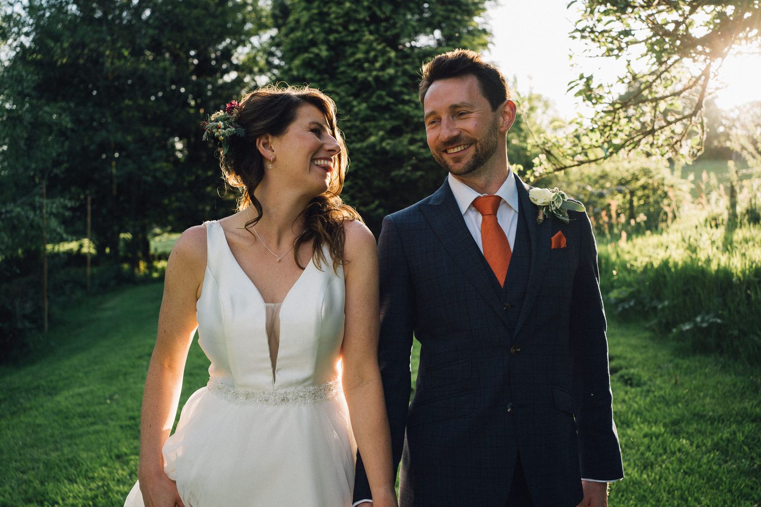 Wedding couple enjoying a romantic moment in a grassy field at sunset.